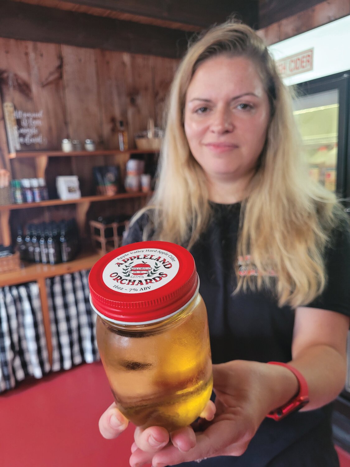 HARD WORK: New Appleland co-owner Ashley Shields holds a jar of freshly fermented hard apple cider, a new offering at the Smithfield orchard store.